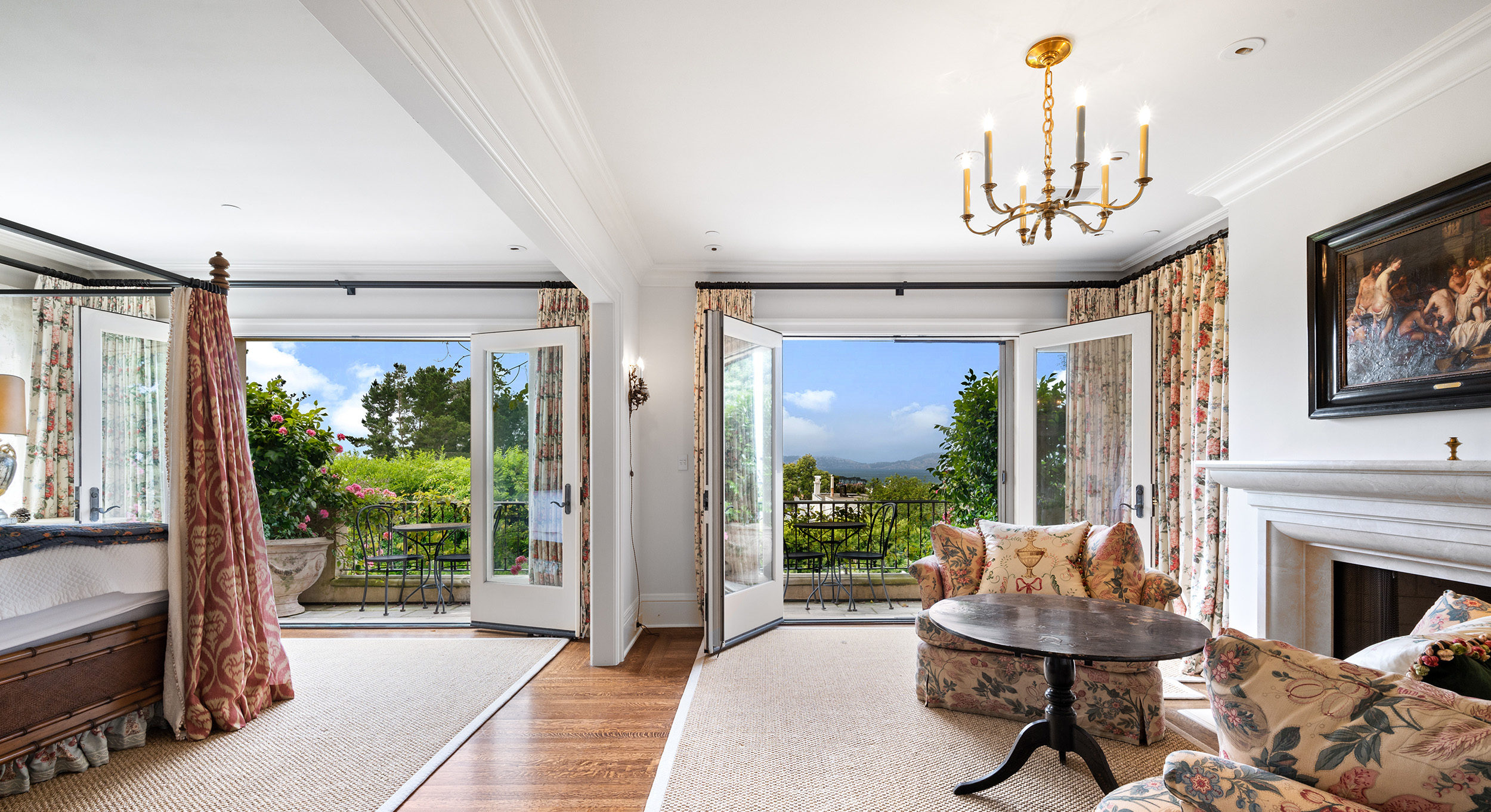 A large primary suite with views of the San Francisco bay visible via two large French doors